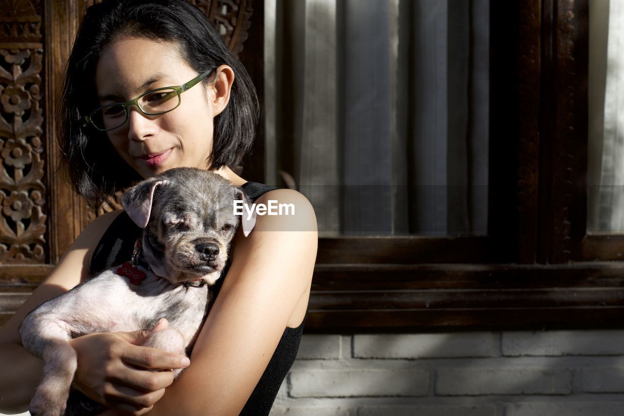 Young woman with dog standing by window