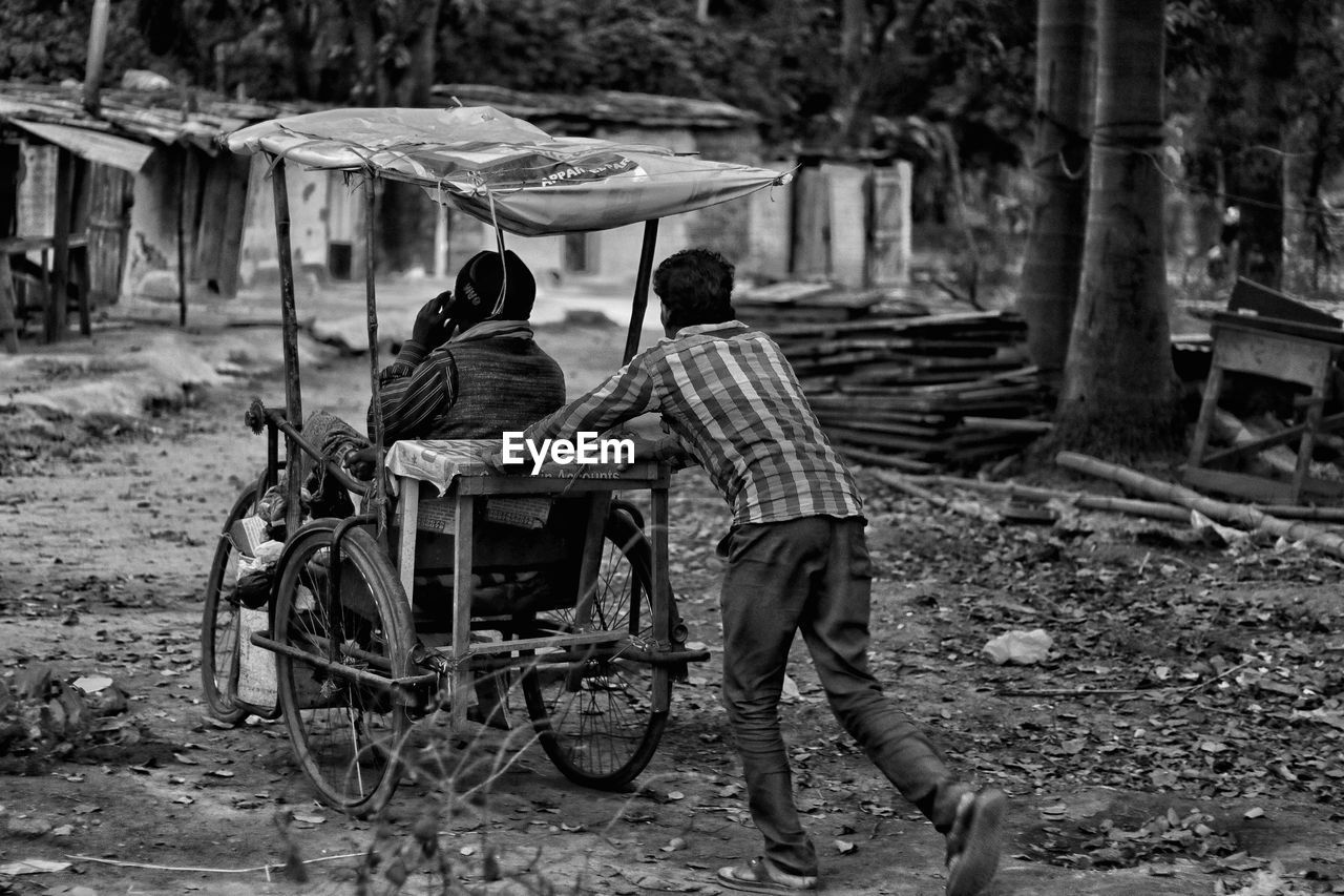 REAR VIEW OF A MAN WITH WOMAN IN CART