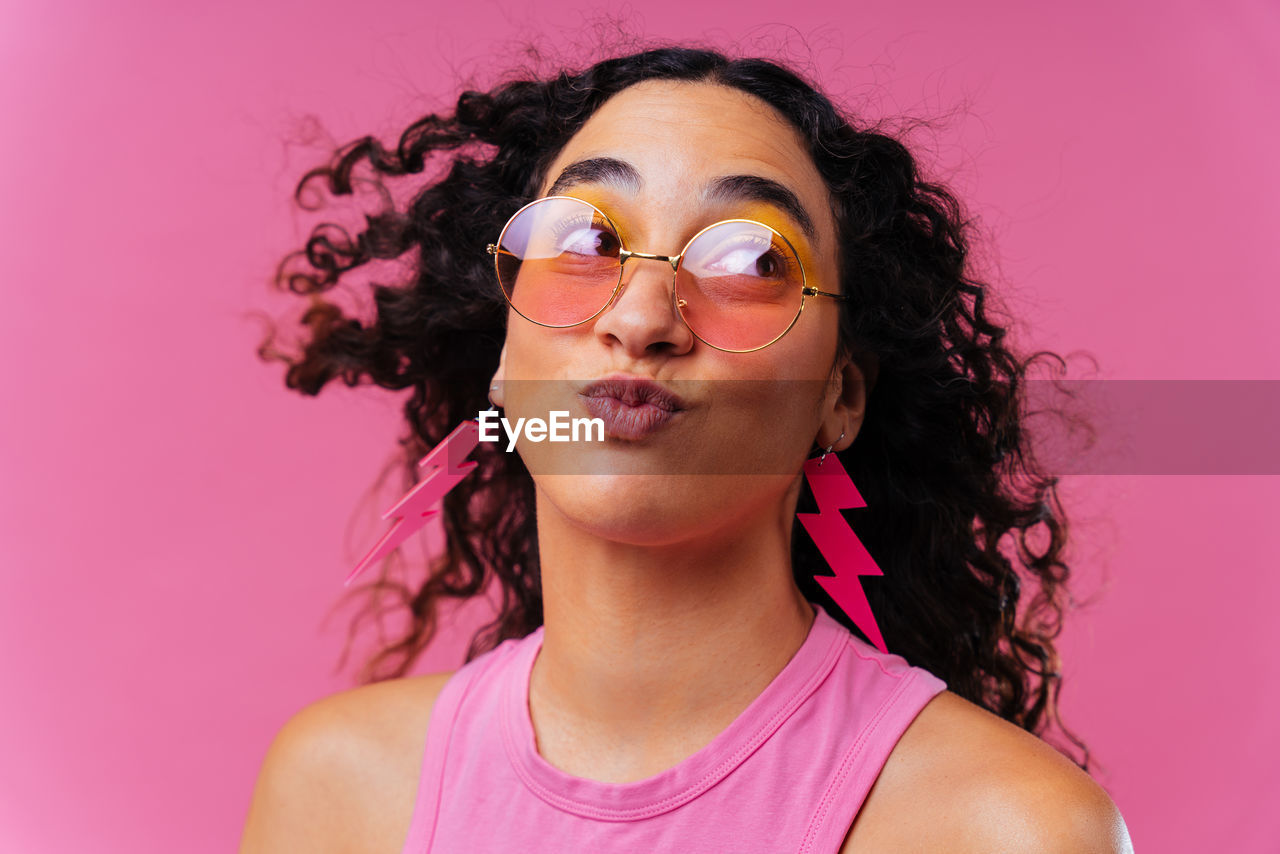 portrait of young woman wearing sunglasses while standing against yellow background