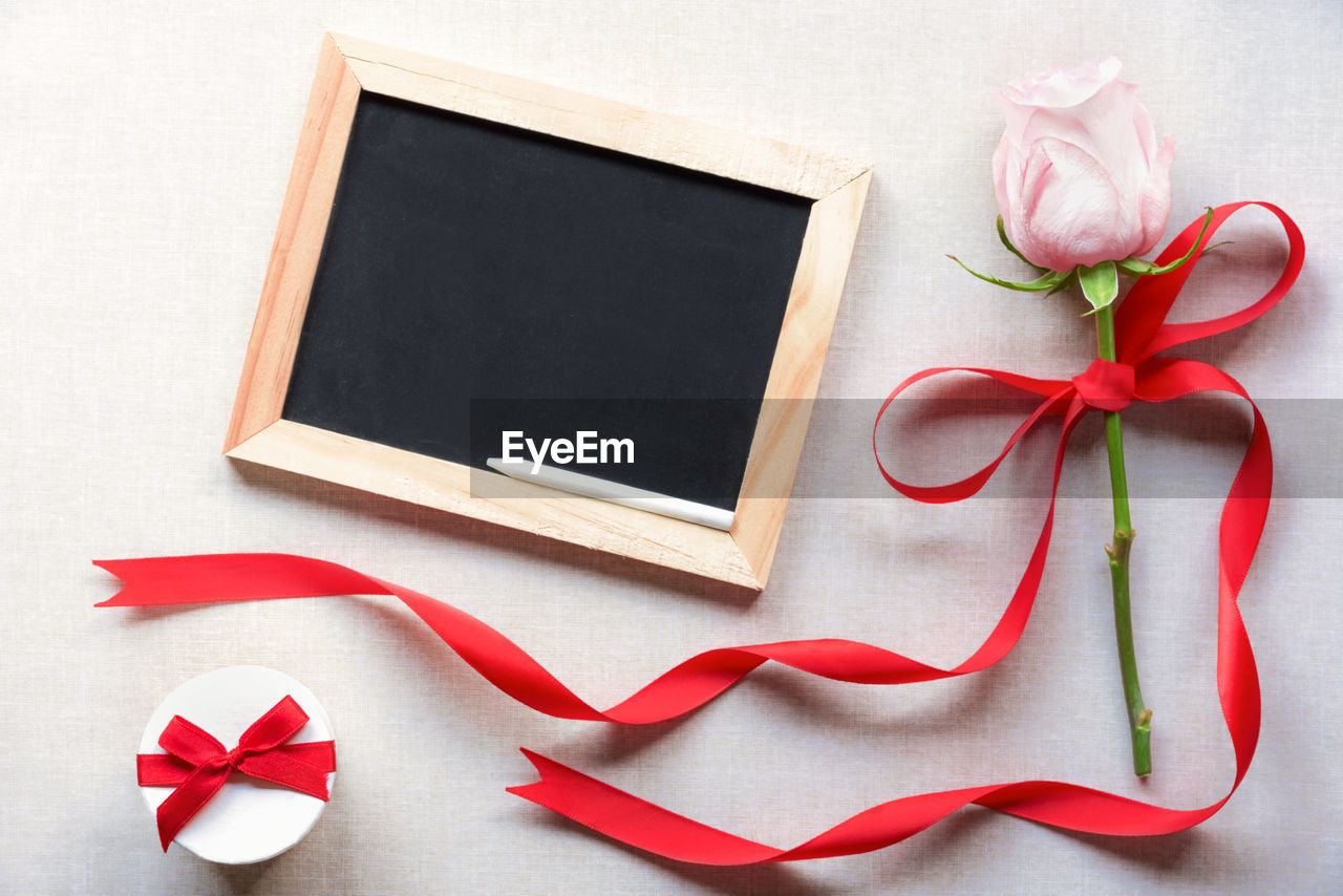 Close-up of rose with blackboard on table