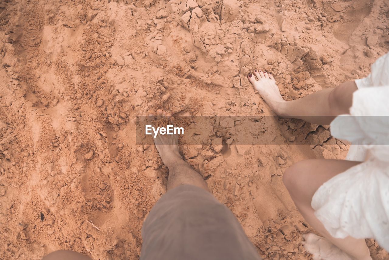 Low section of couple walking at beach