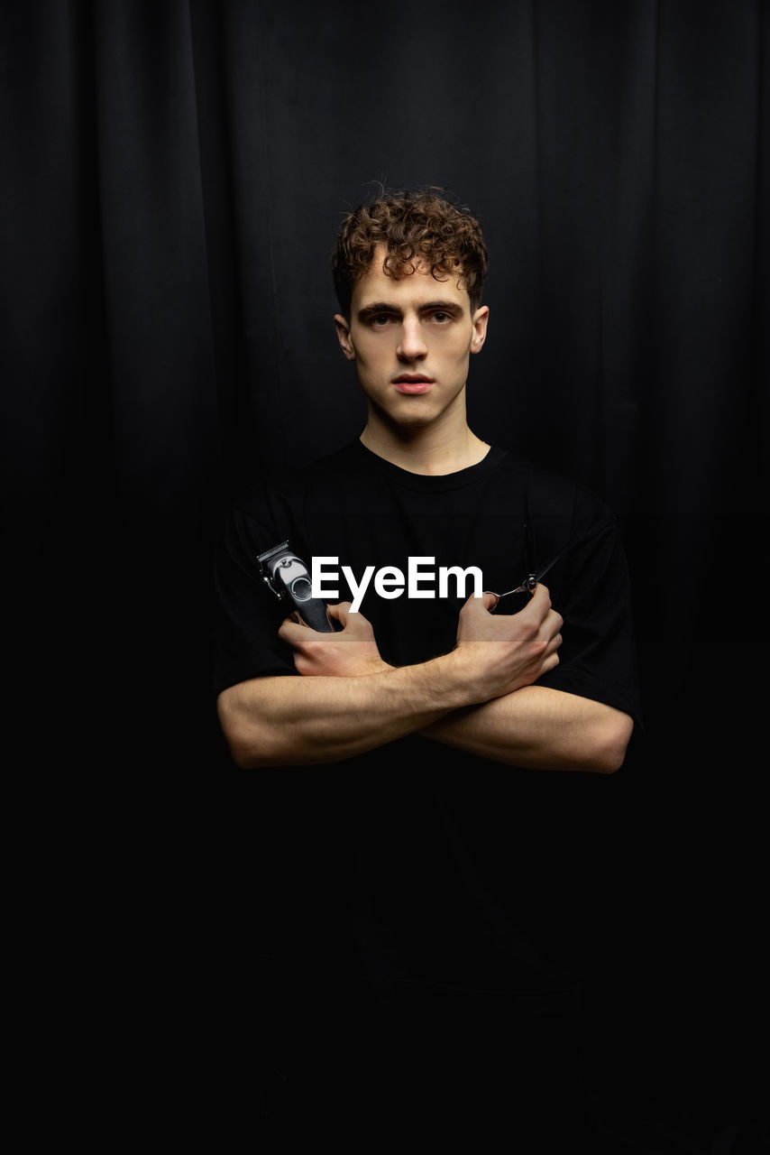 Portrait of young man exercising against black background