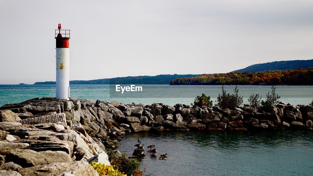 Lighthouse by sea against sky