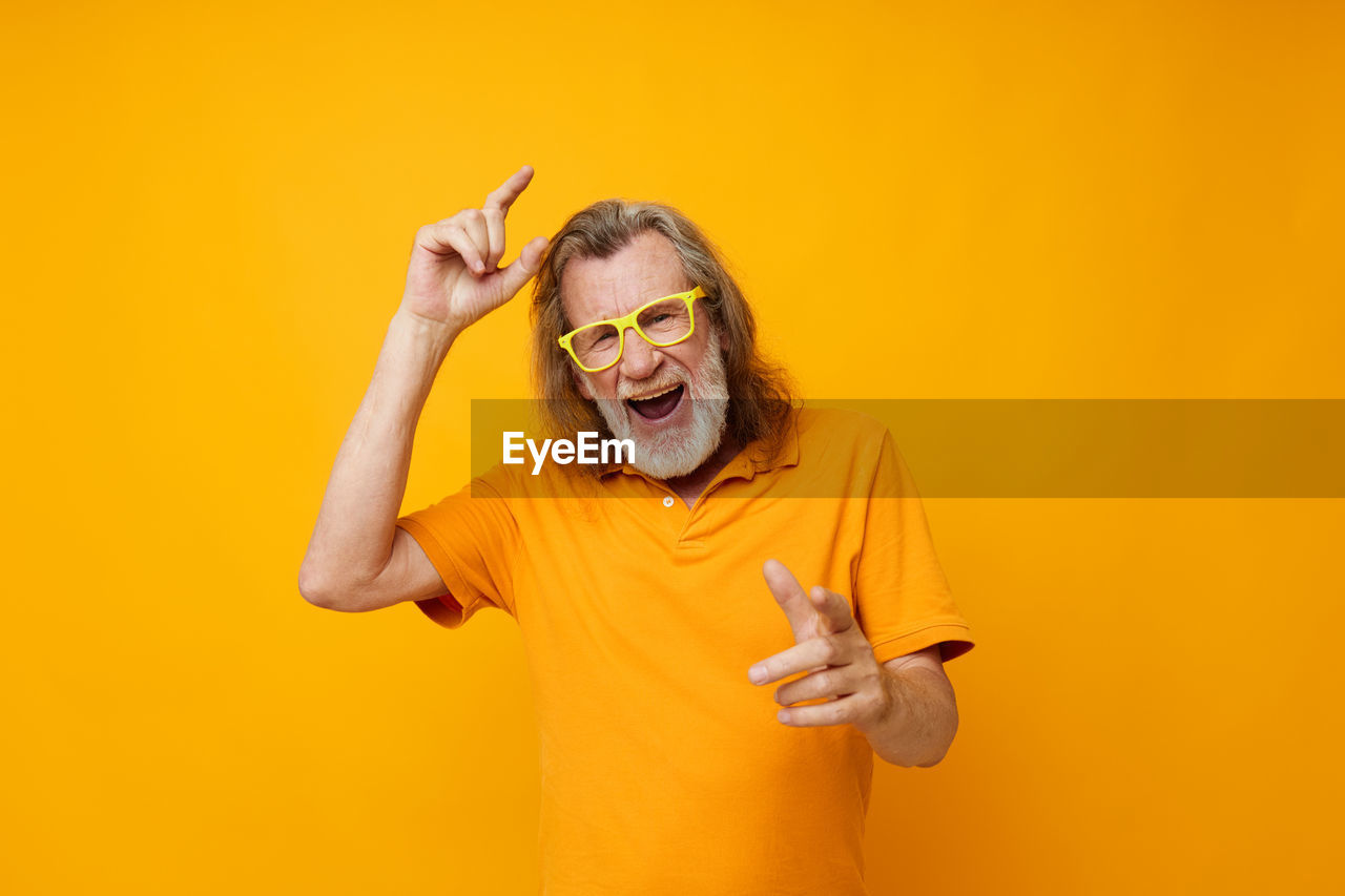 Portrait of senior man against yellow background