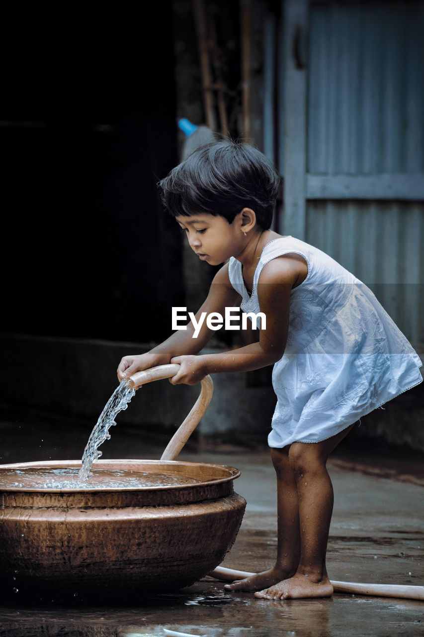 Side view of girl filling water in container