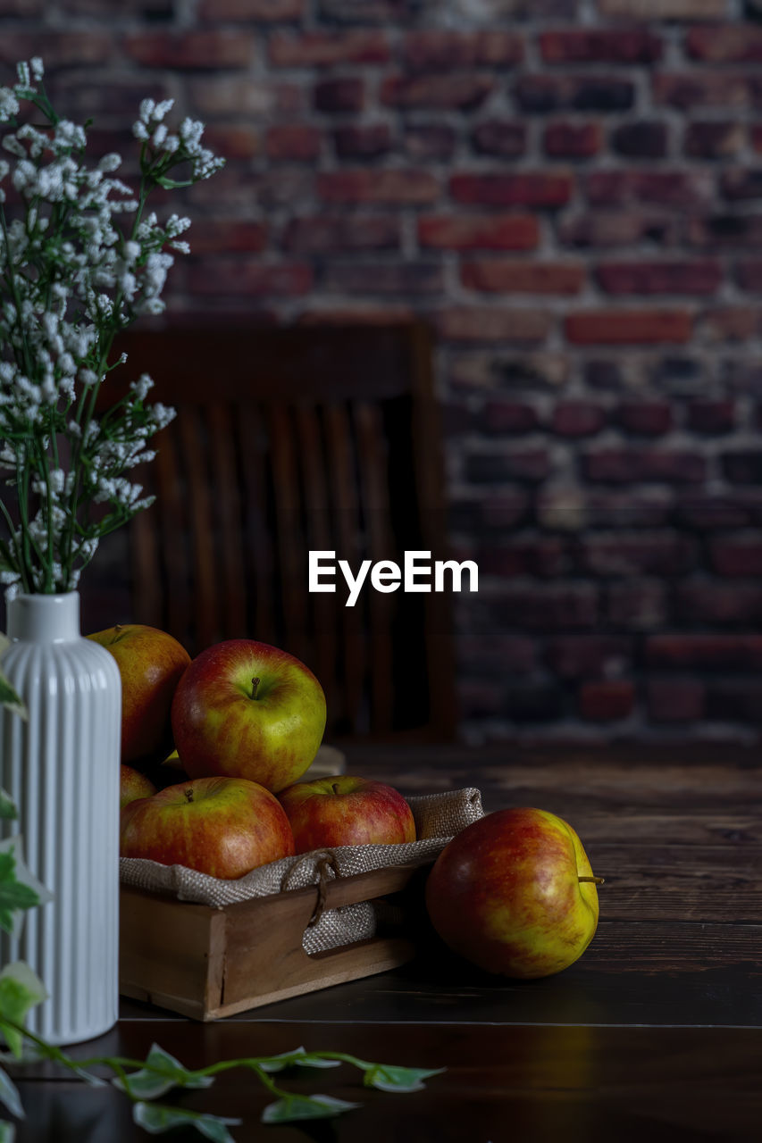 Apple on a wooden table as backdrop.background red brick wall.
