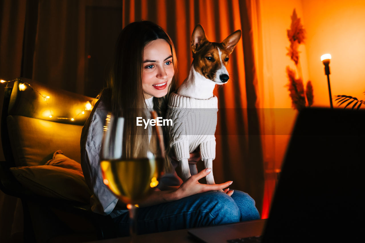Portrait of smiling young woman sitting at home with dog