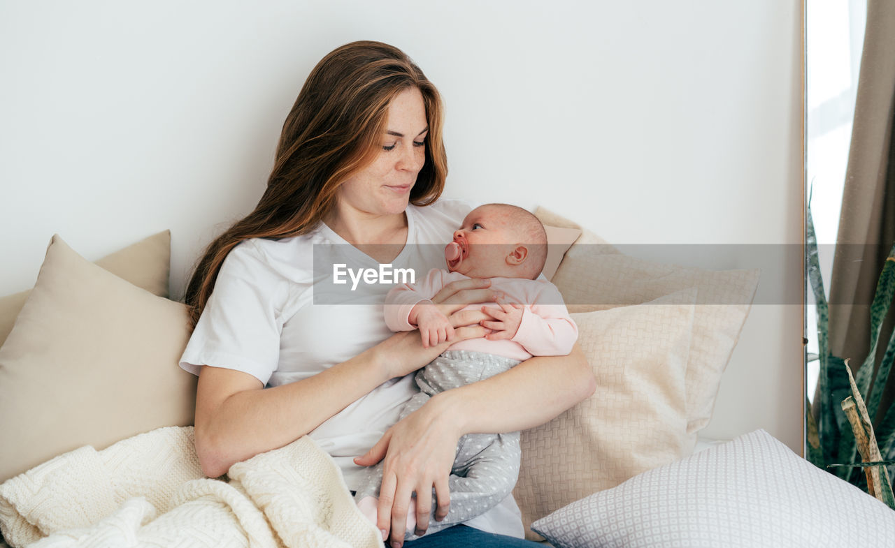 Young caucasian mother with a one-month baby in her arms.