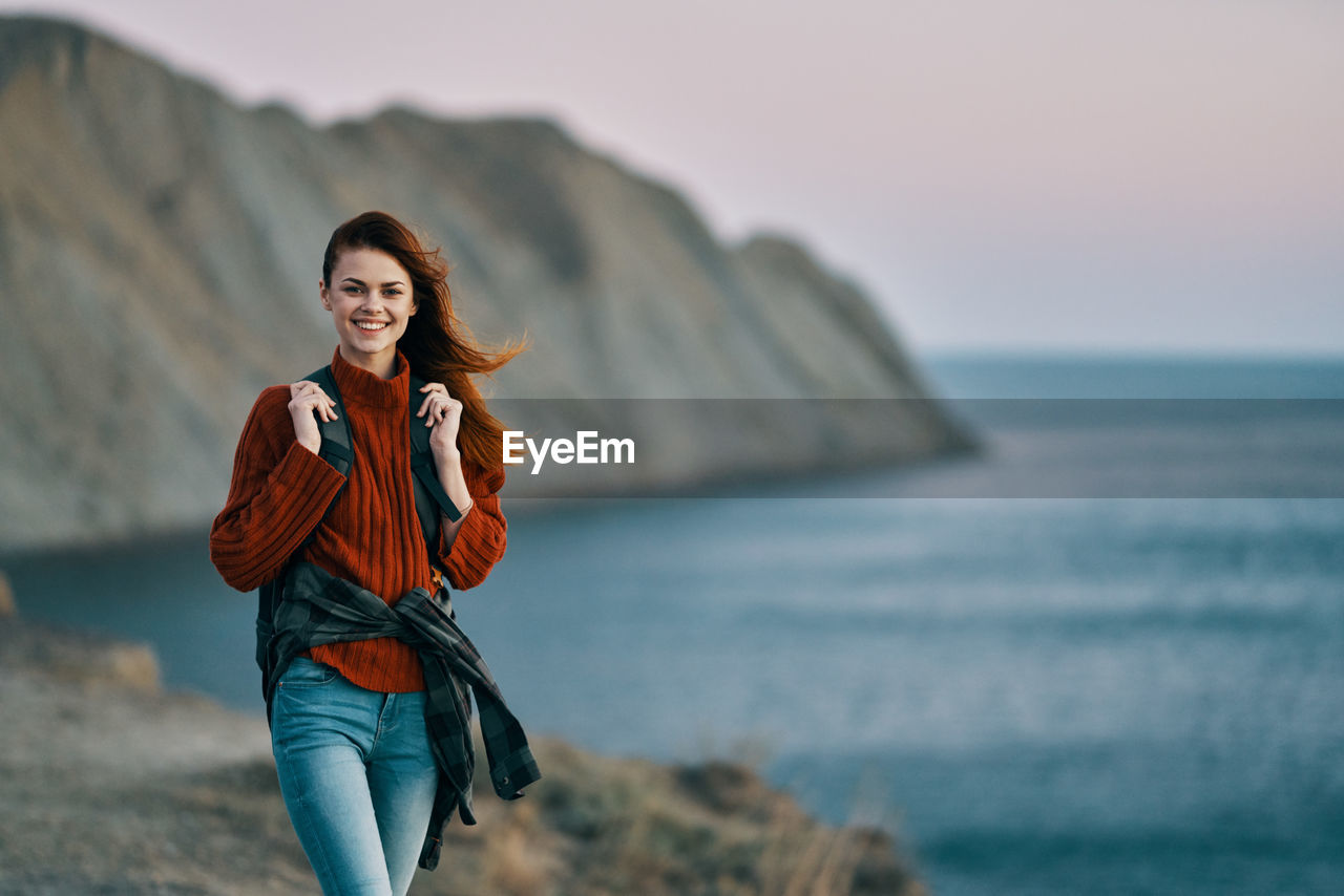 PORTRAIT OF YOUNG WOMAN AT BEACH