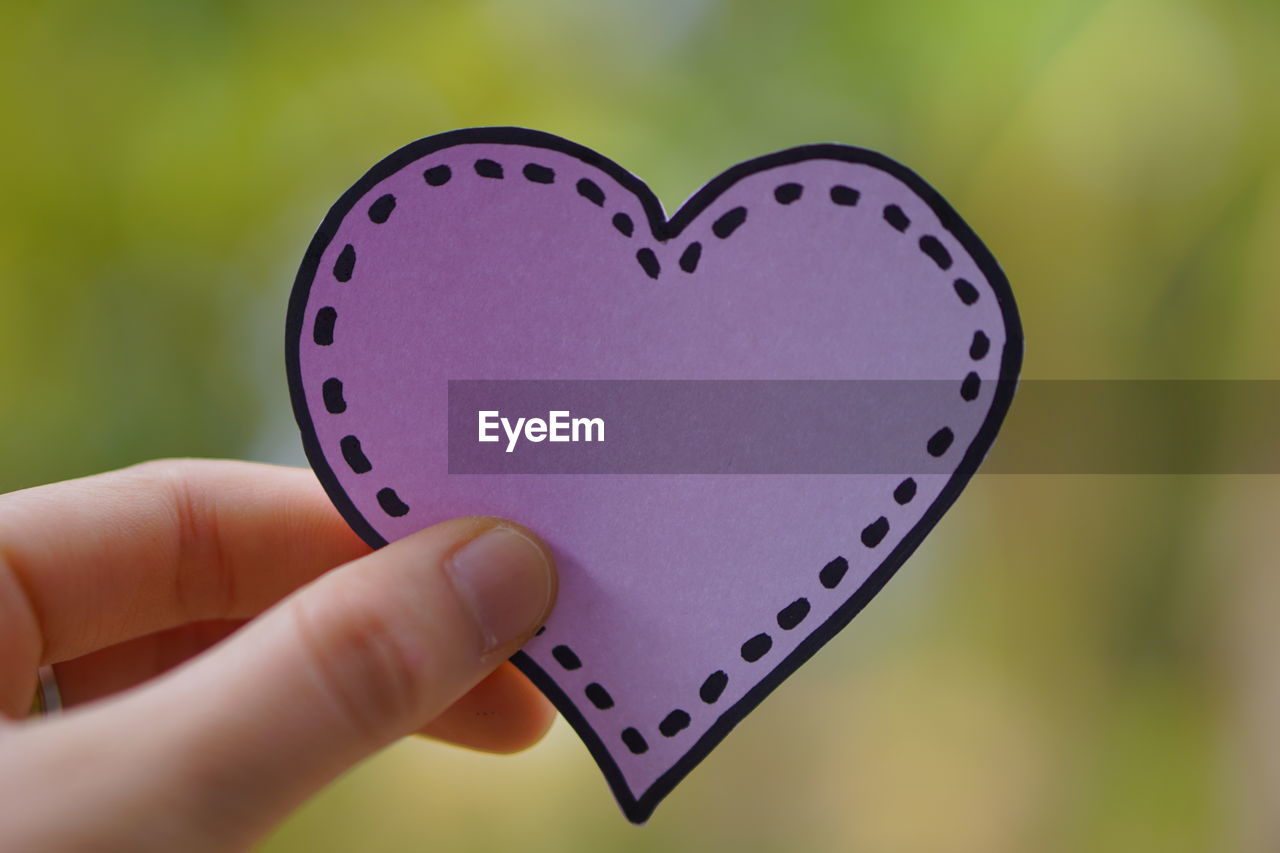 Close-up of woman holding heart shape hand