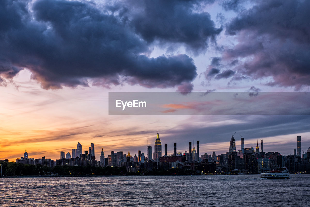 SEA AND BUILDINGS AGAINST SKY AT SUNSET