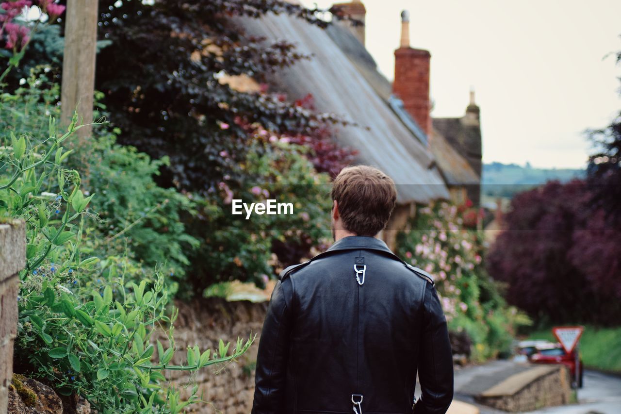 Rear view of man standing by plants against building