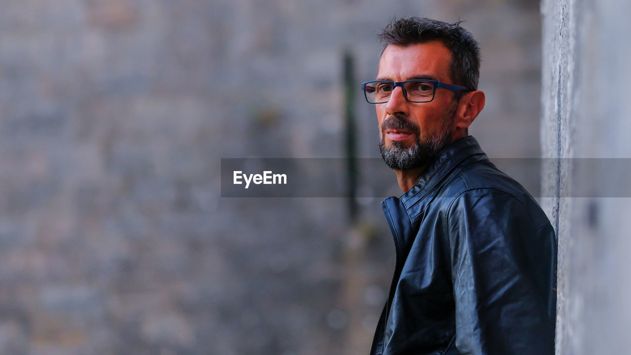 Portrait of man standing against wall