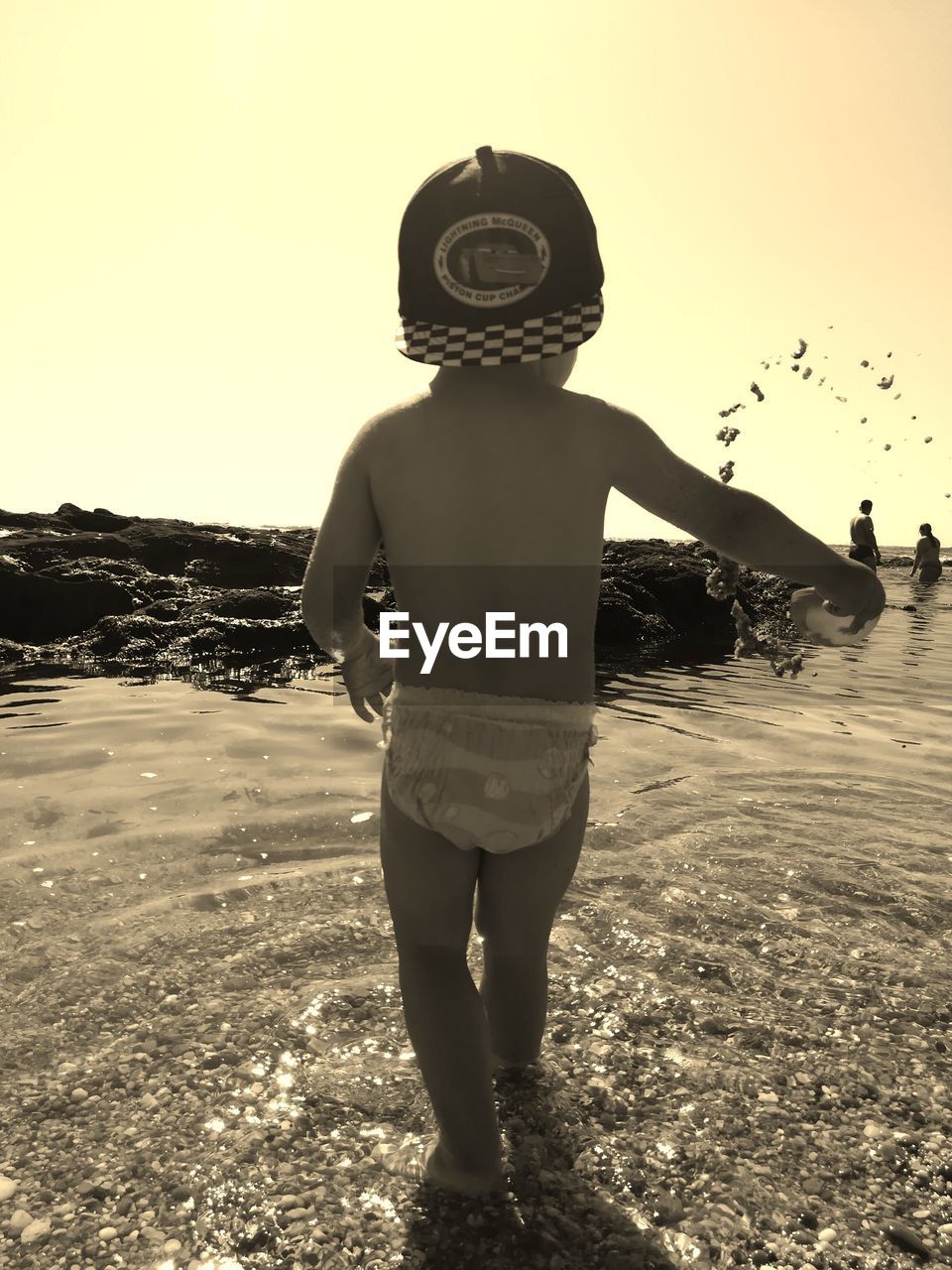 REAR VIEW OF BOY STANDING AT BEACH