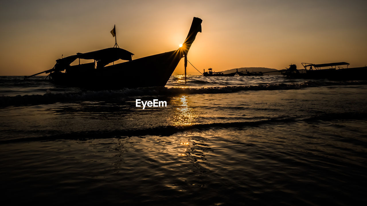 Silhouette of sailboat in sea against sky during sunset