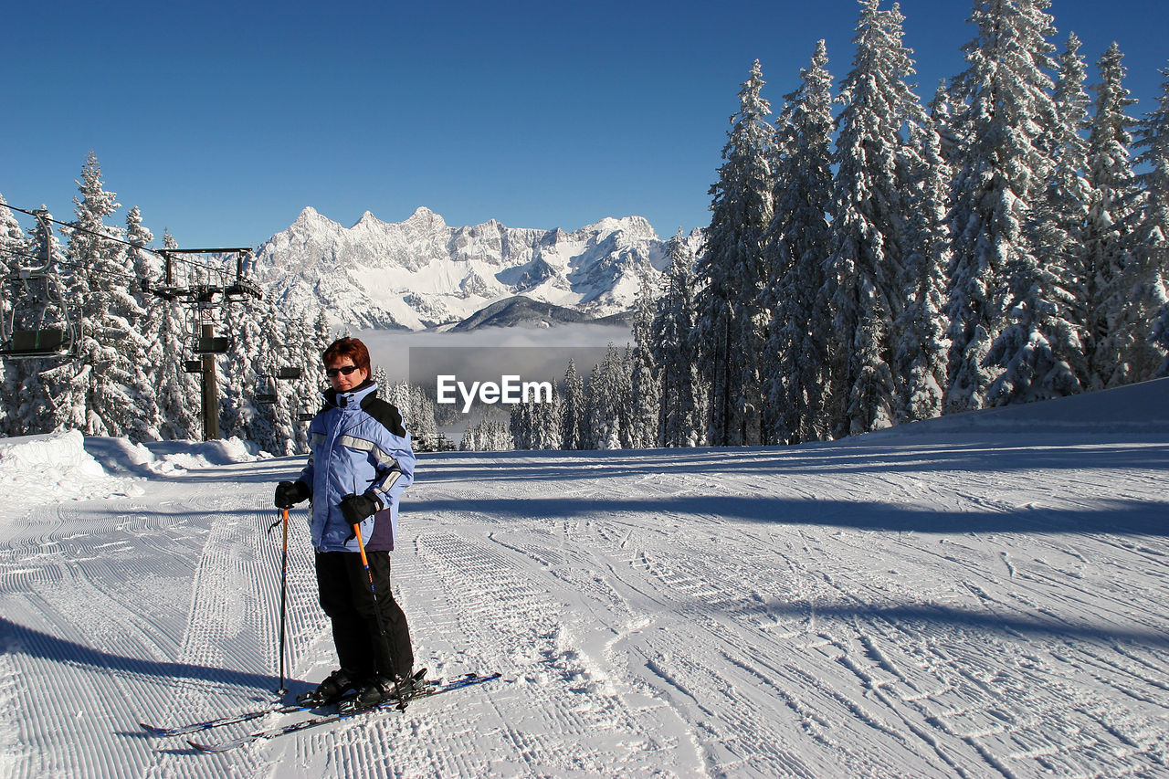 Full length of woman skiing on snow covered landscape during winter