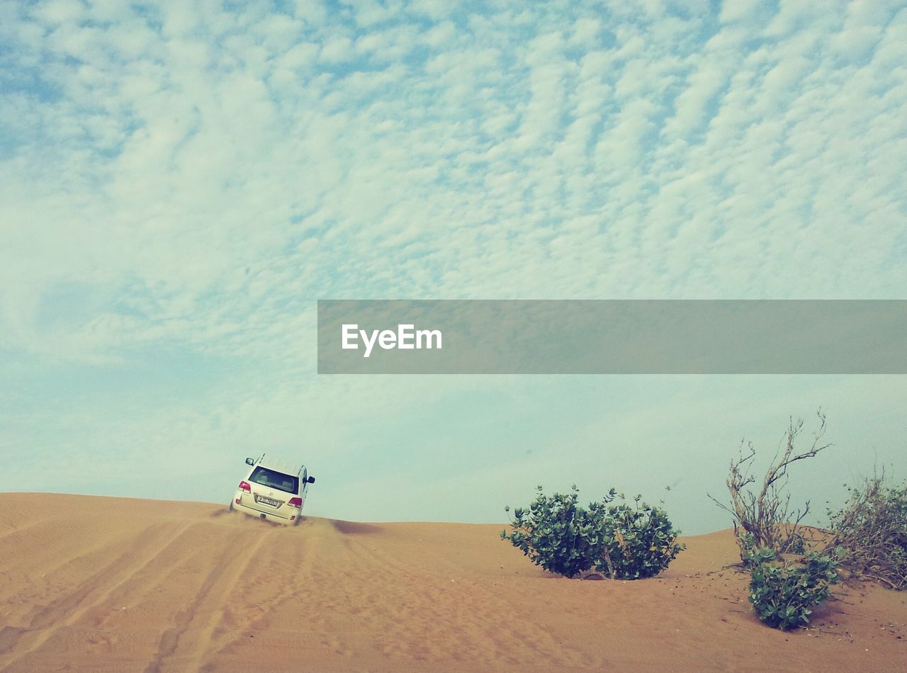 Car on desert against sky