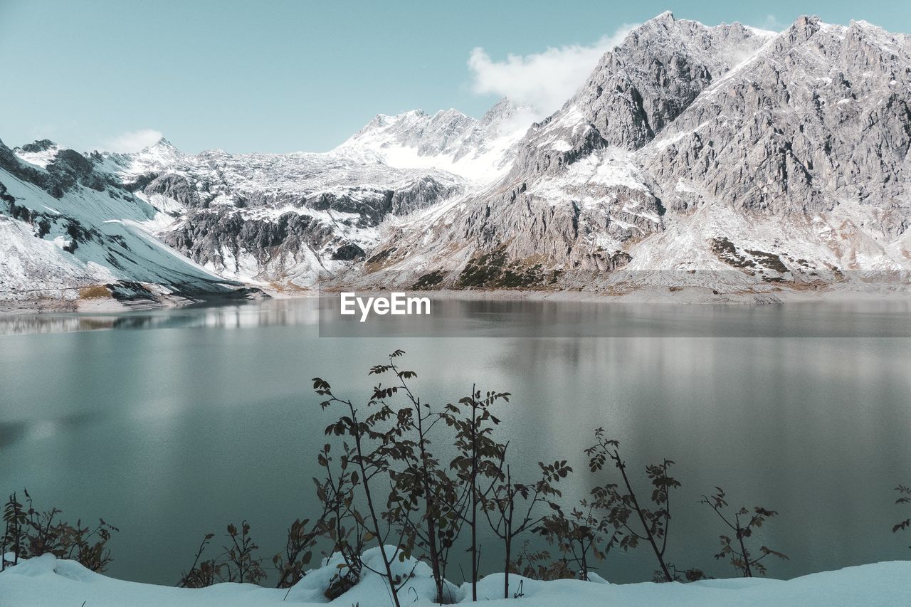 Scenic view of lake by snowcapped mountains against sky 