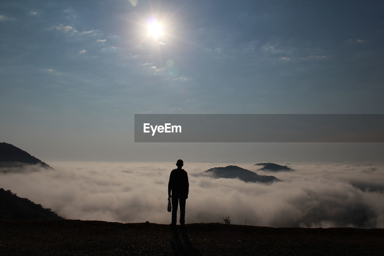 Rear view of silhouette man standing by cloudscape