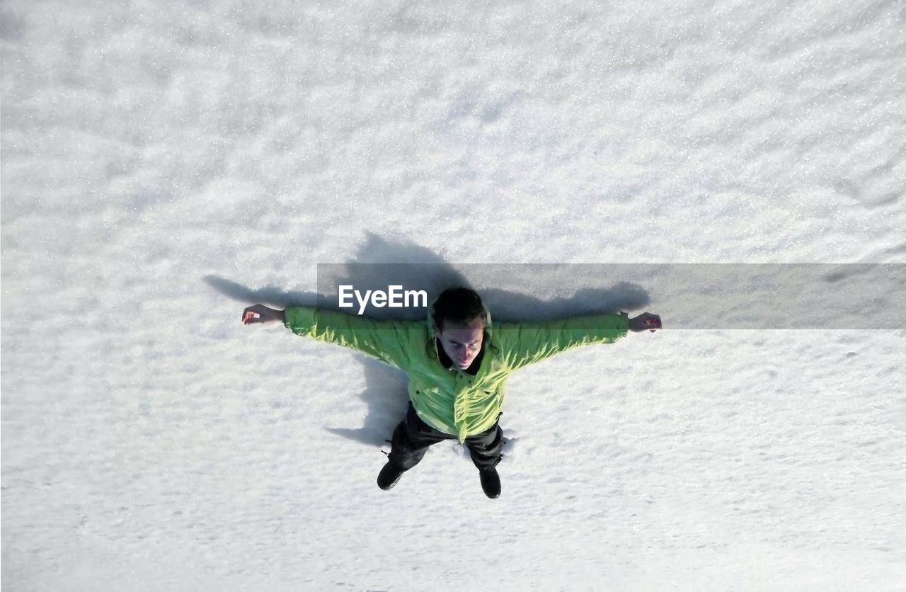 High angle view of man lying on snow covered field