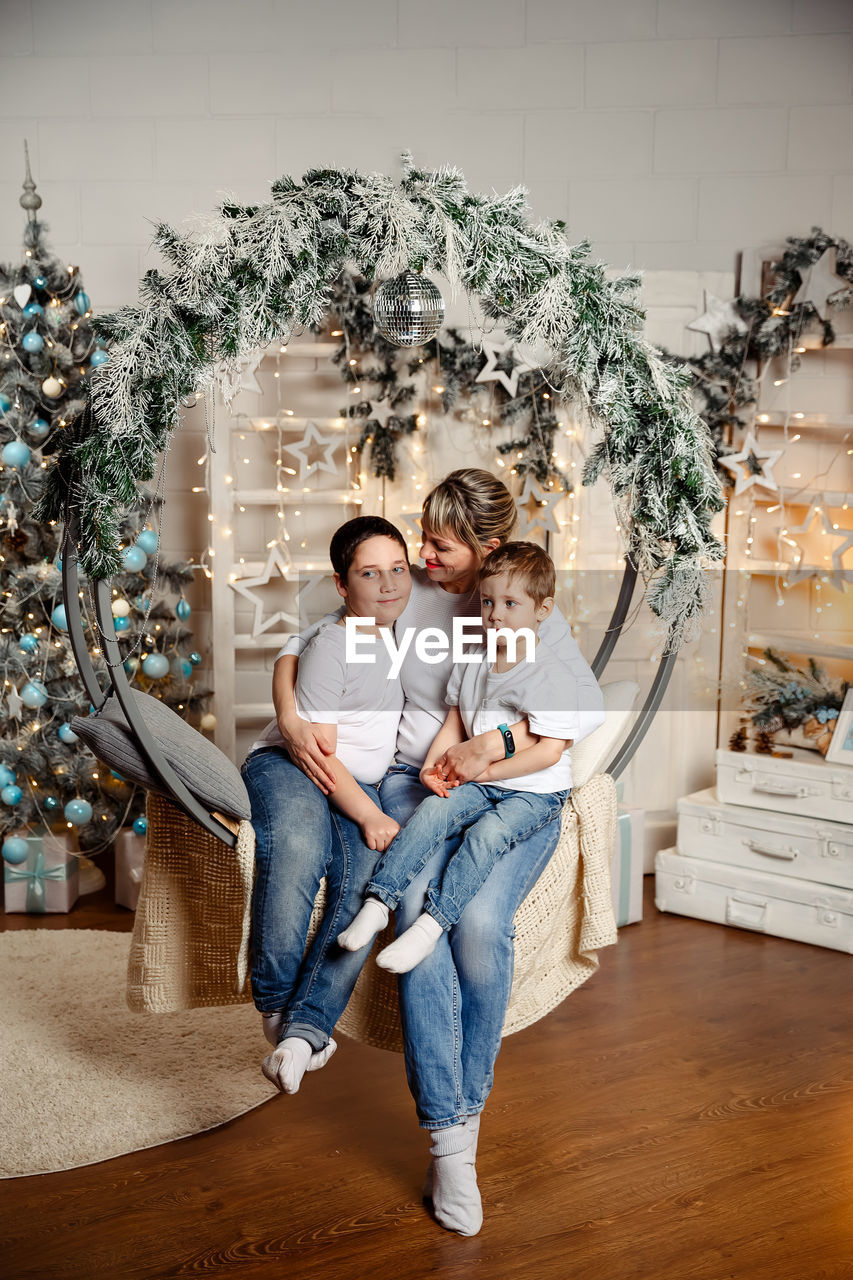 Happy children with mom sits in front of the christmas tree