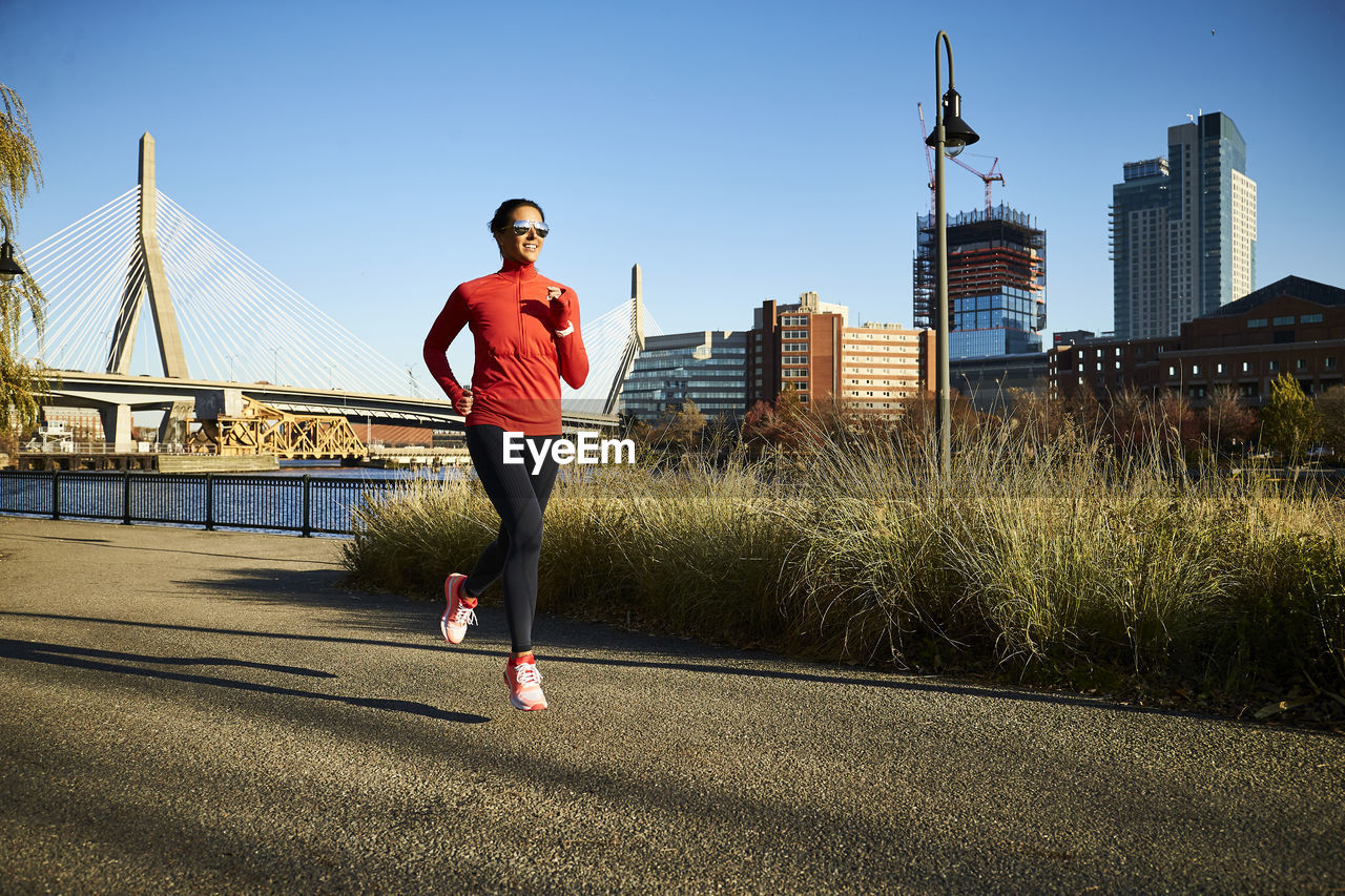 A fit woman runs past the boston skyline.