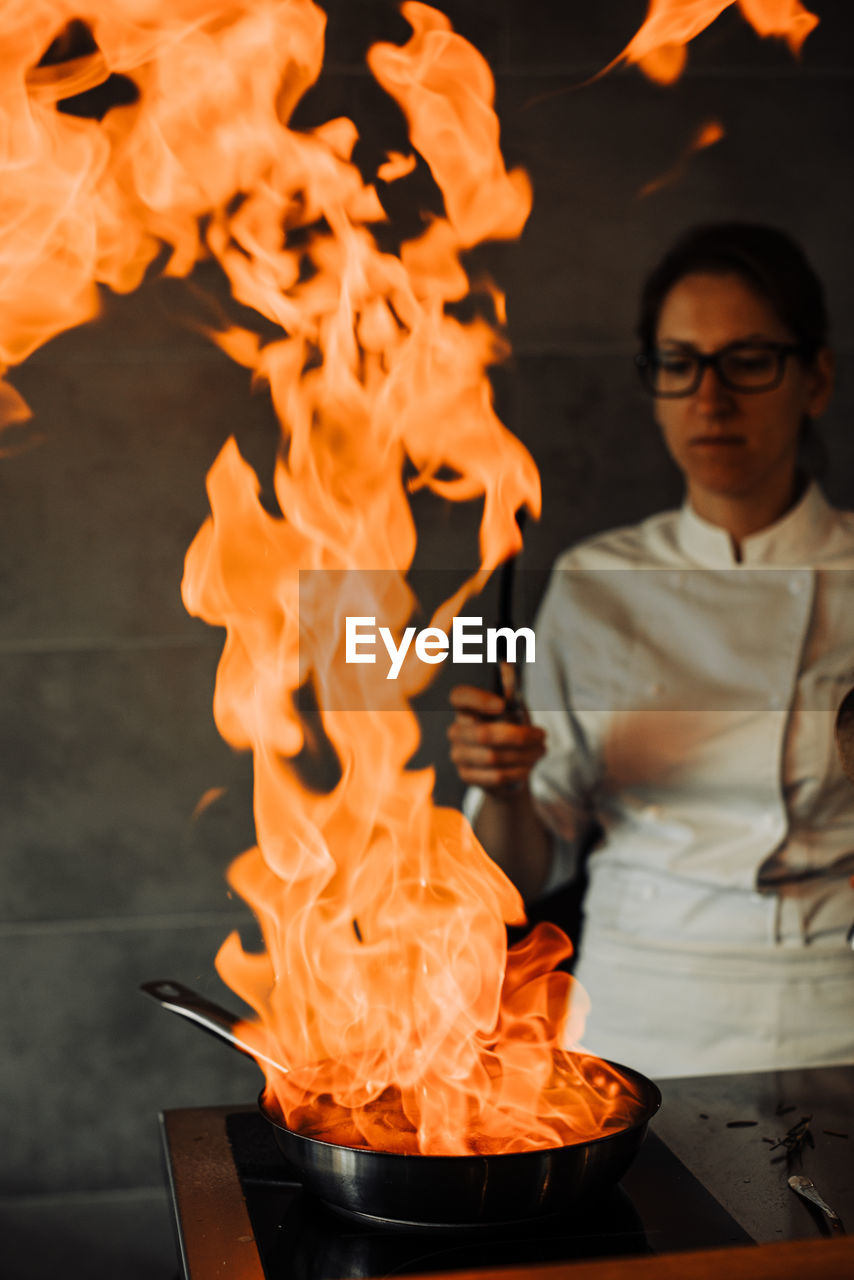 Female chef is making flambé in the restaurant kitchen