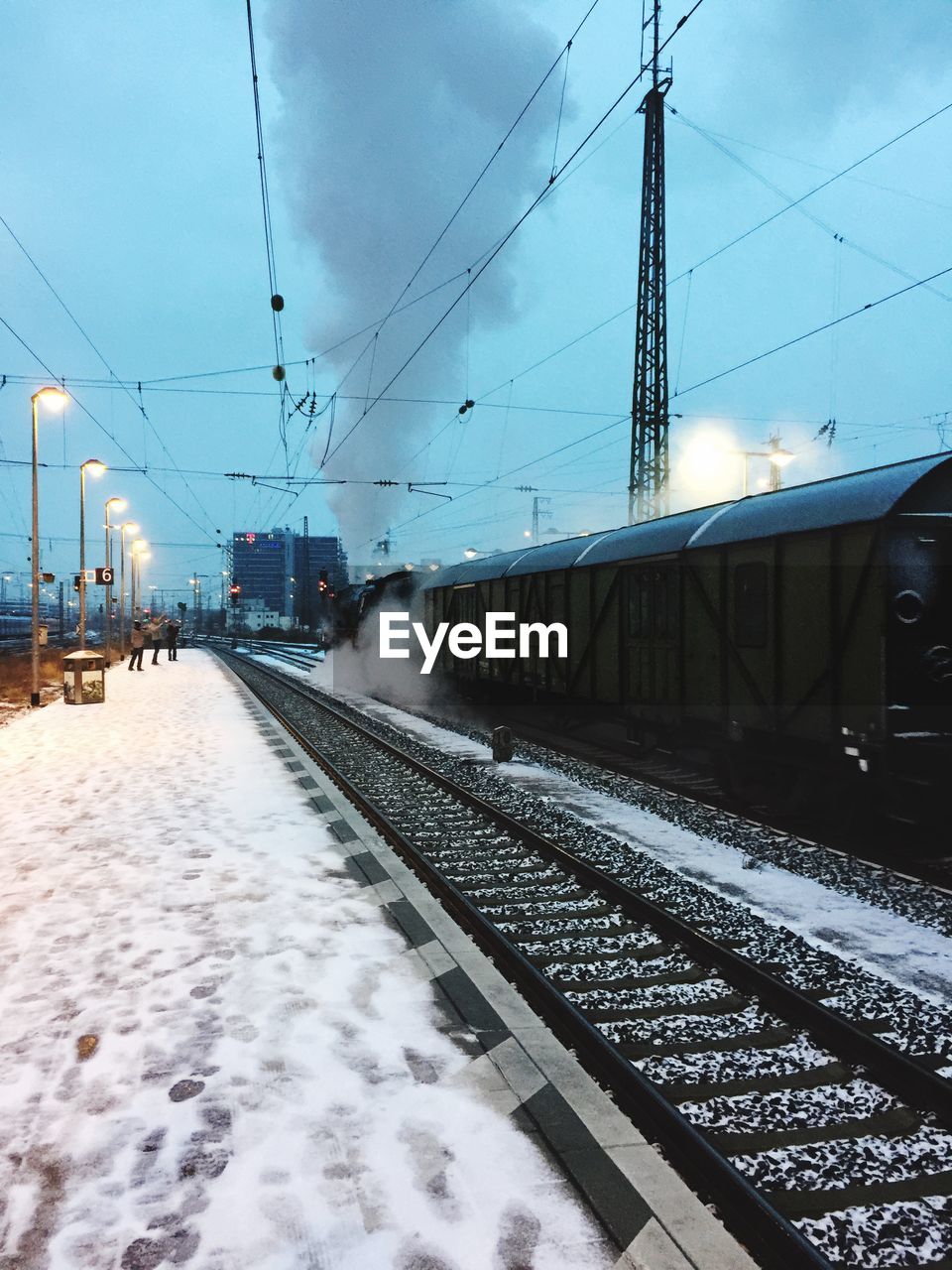 TRAIN ON SNOW COVERED RAILROAD TRACKS AGAINST SKY