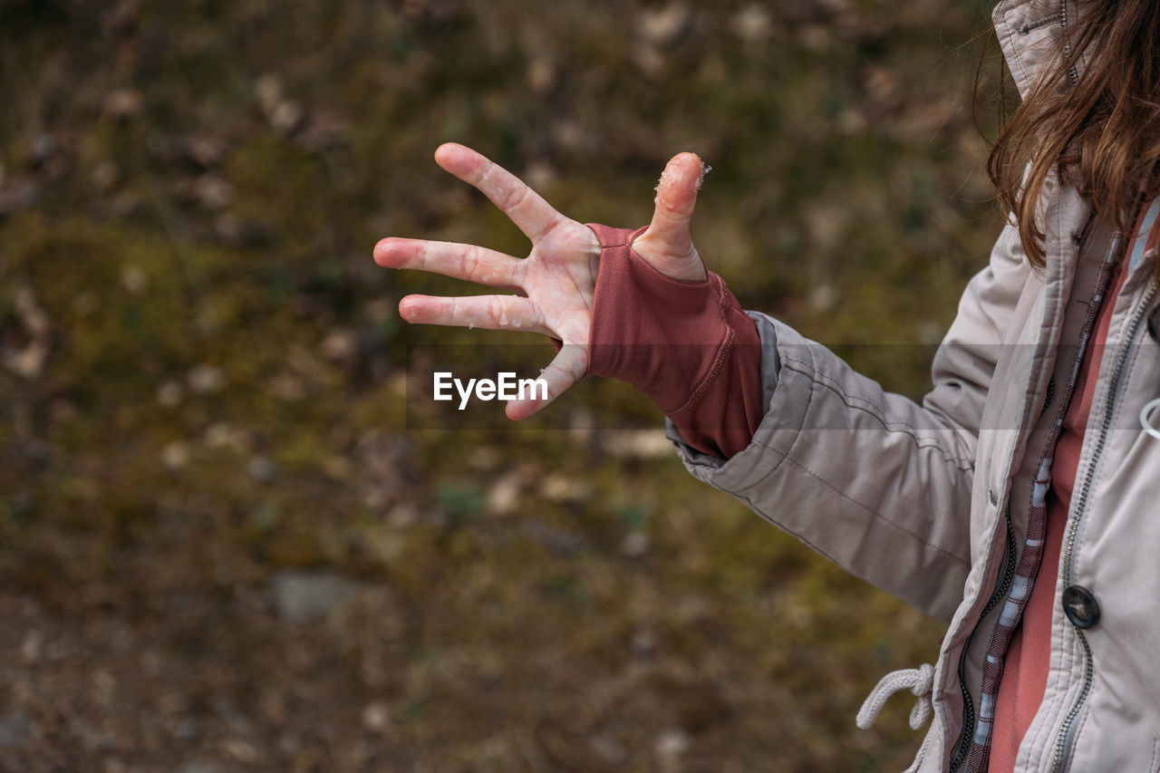 Open palm with particles of snow. wet and cold woman's hand in thumbhole jumper during a hiking 