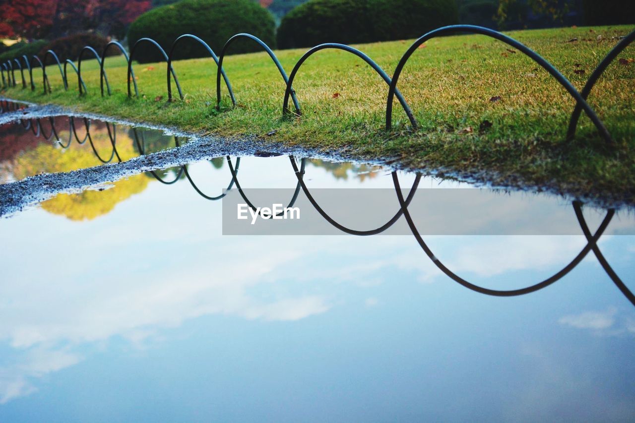 Arch shaped railing by calm stream at park