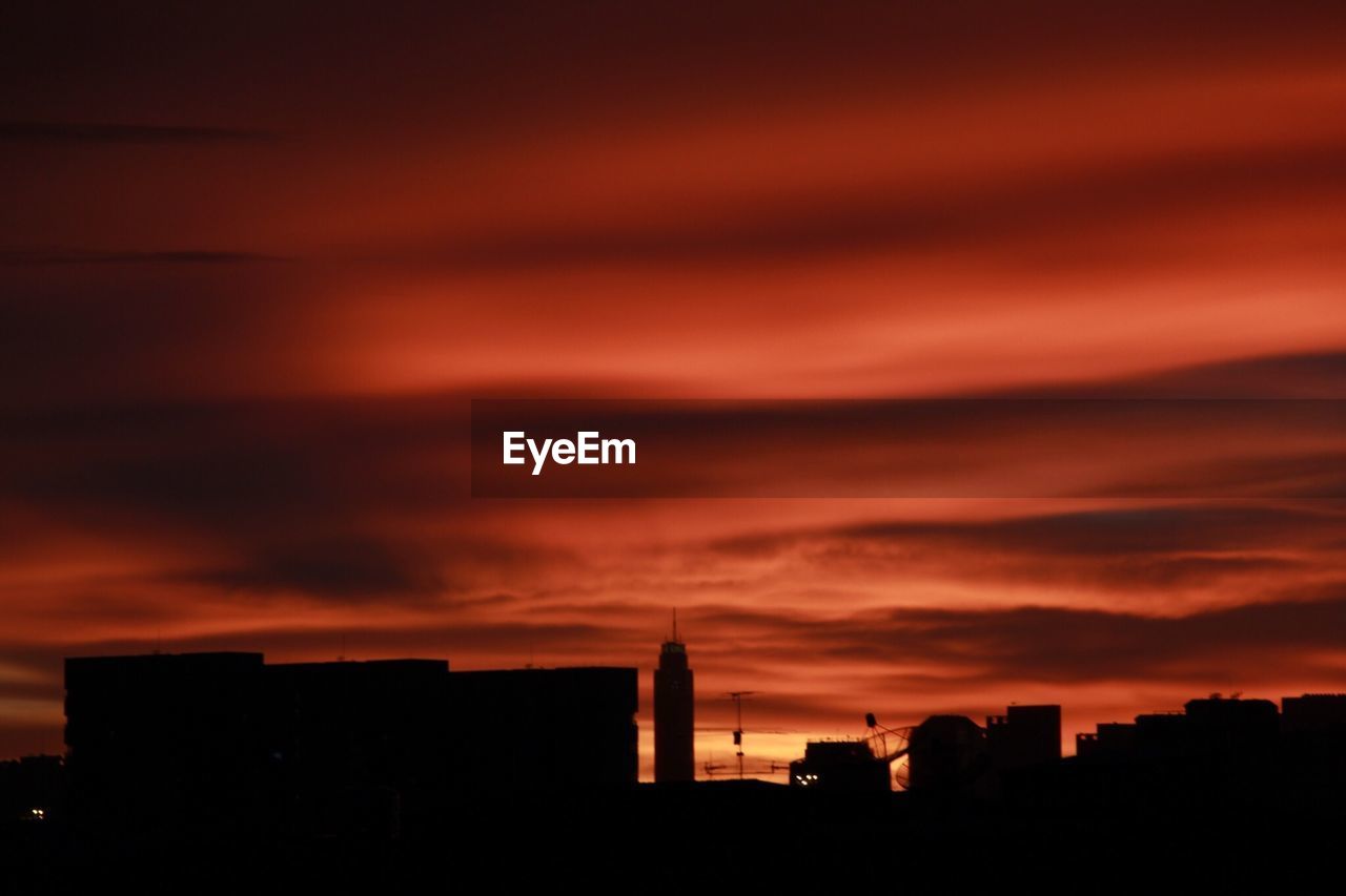SILHOUETTE OF BUILDINGS AGAINST CLOUDY SKY