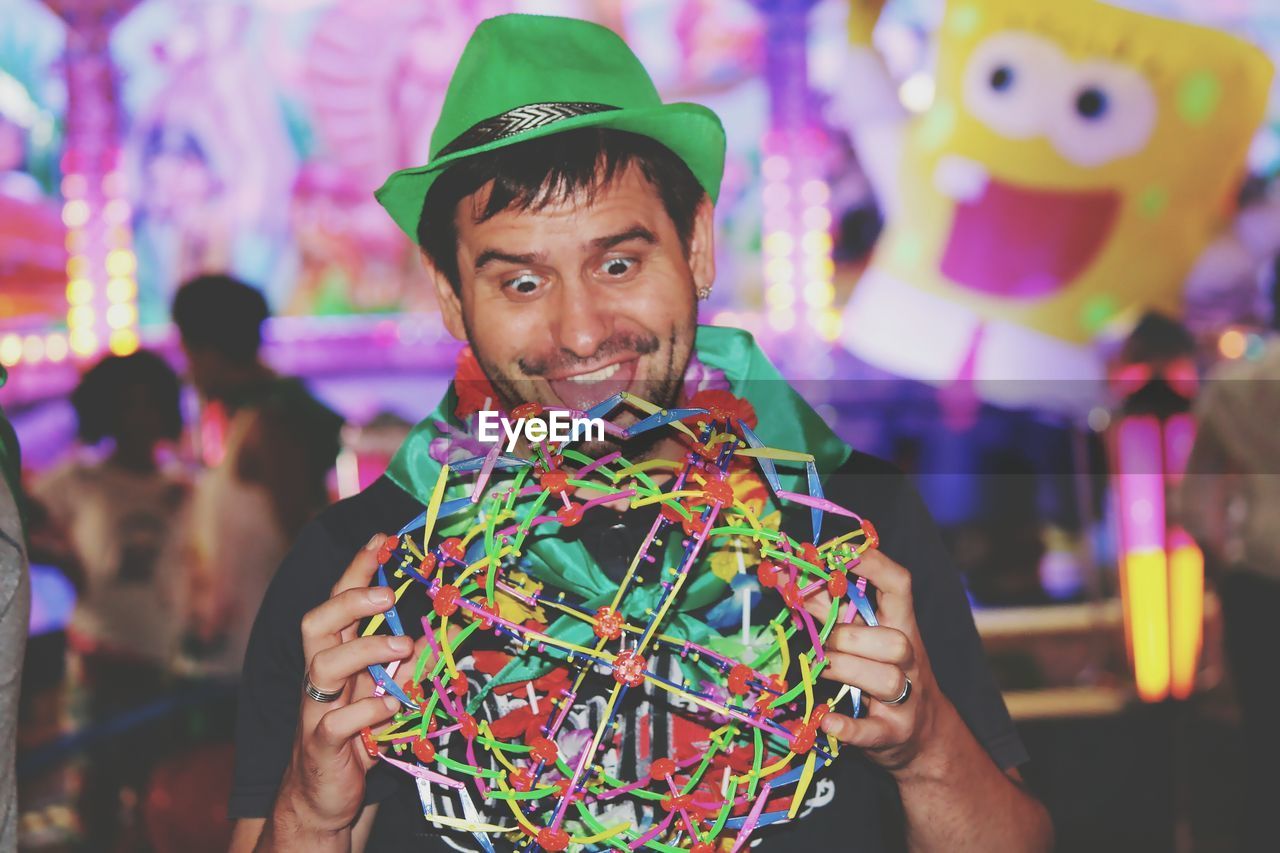 Man making face while holding colorful ball at night during carnival