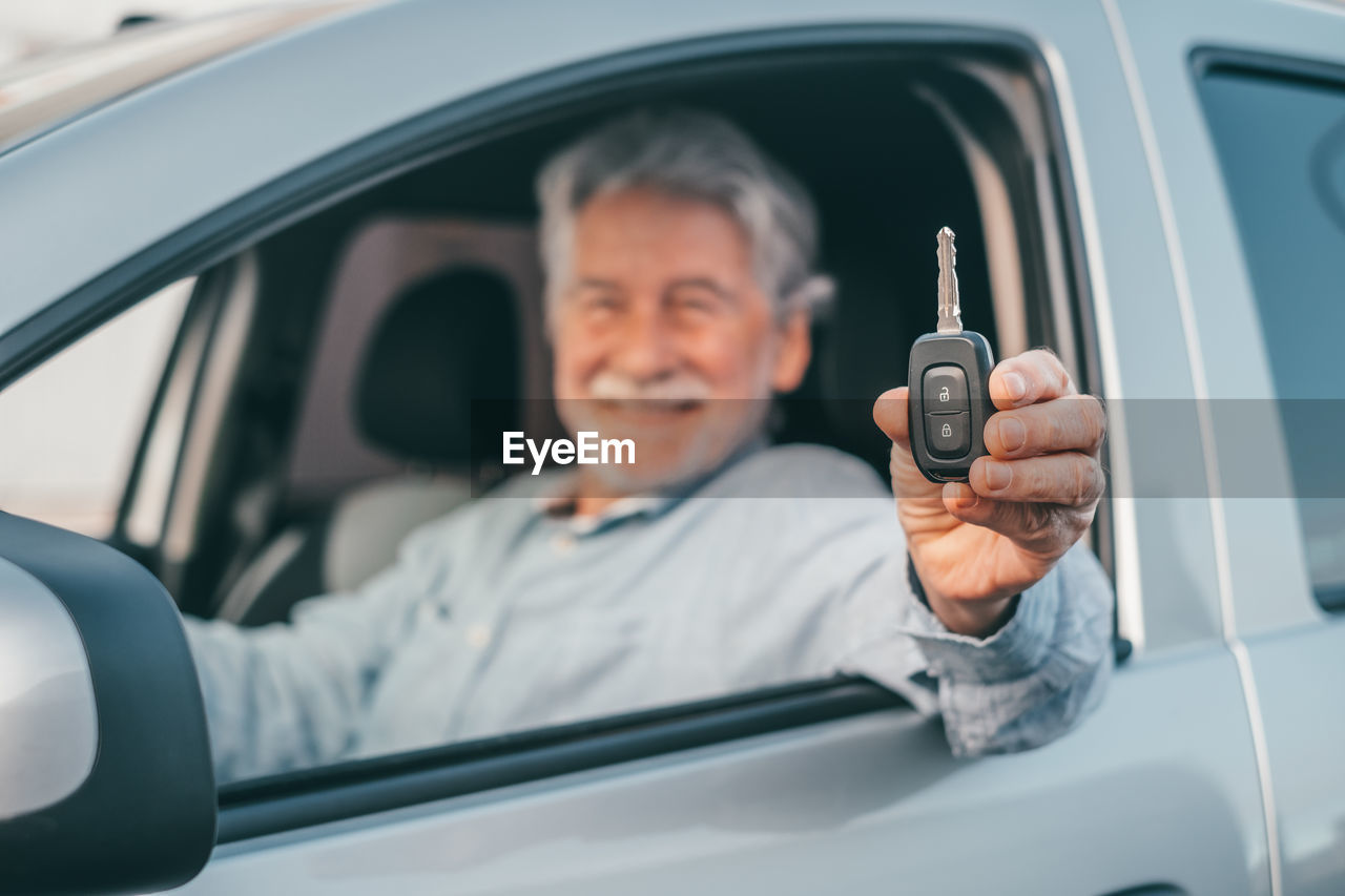 Portrait of senior man holding car key while sitting in car