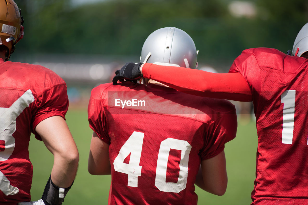 Rear view of american football players on field