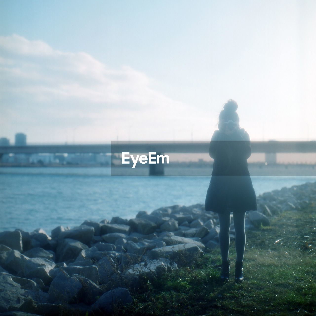 Woman standing on riverbank against sky