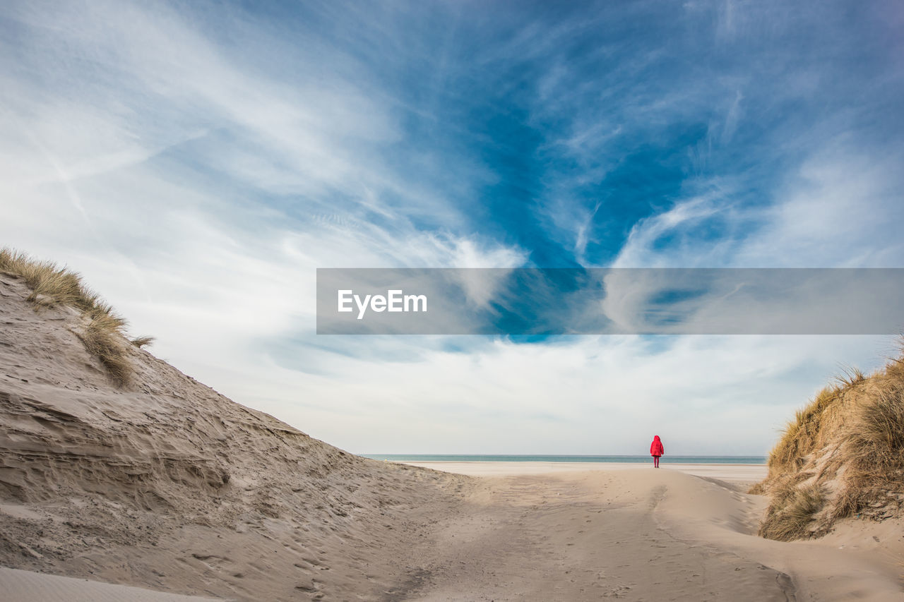 Mid distance of woman walking at beach against sky