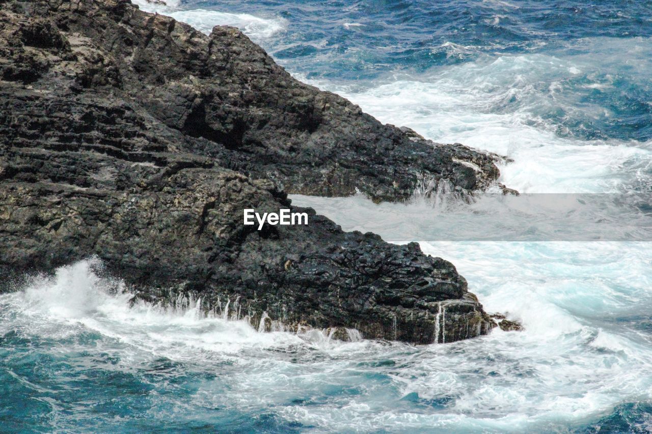 High angle view of waves crashing rock