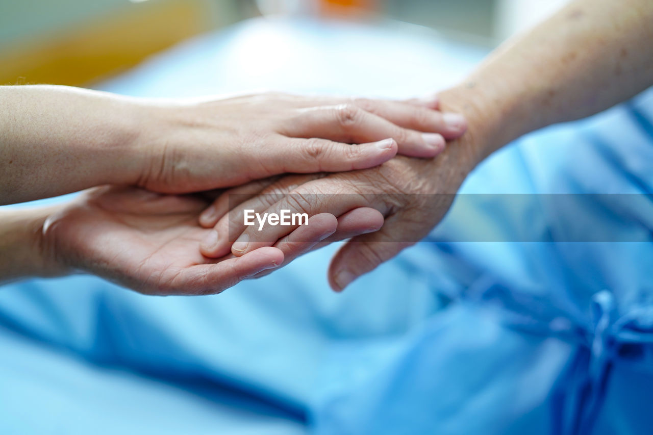 Cropped image of doctor and patient holding hands in hospital