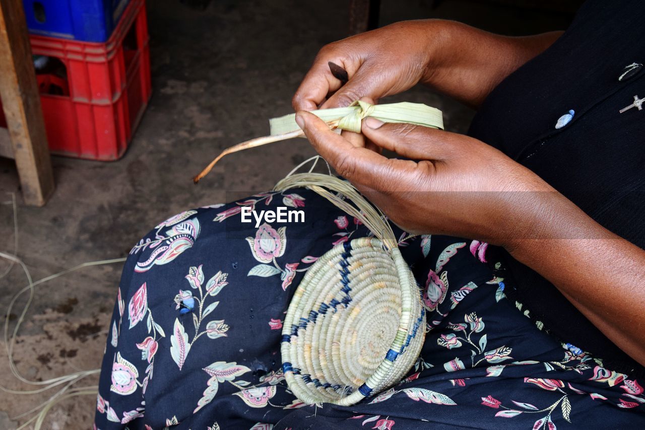 Midsection of woman making basket