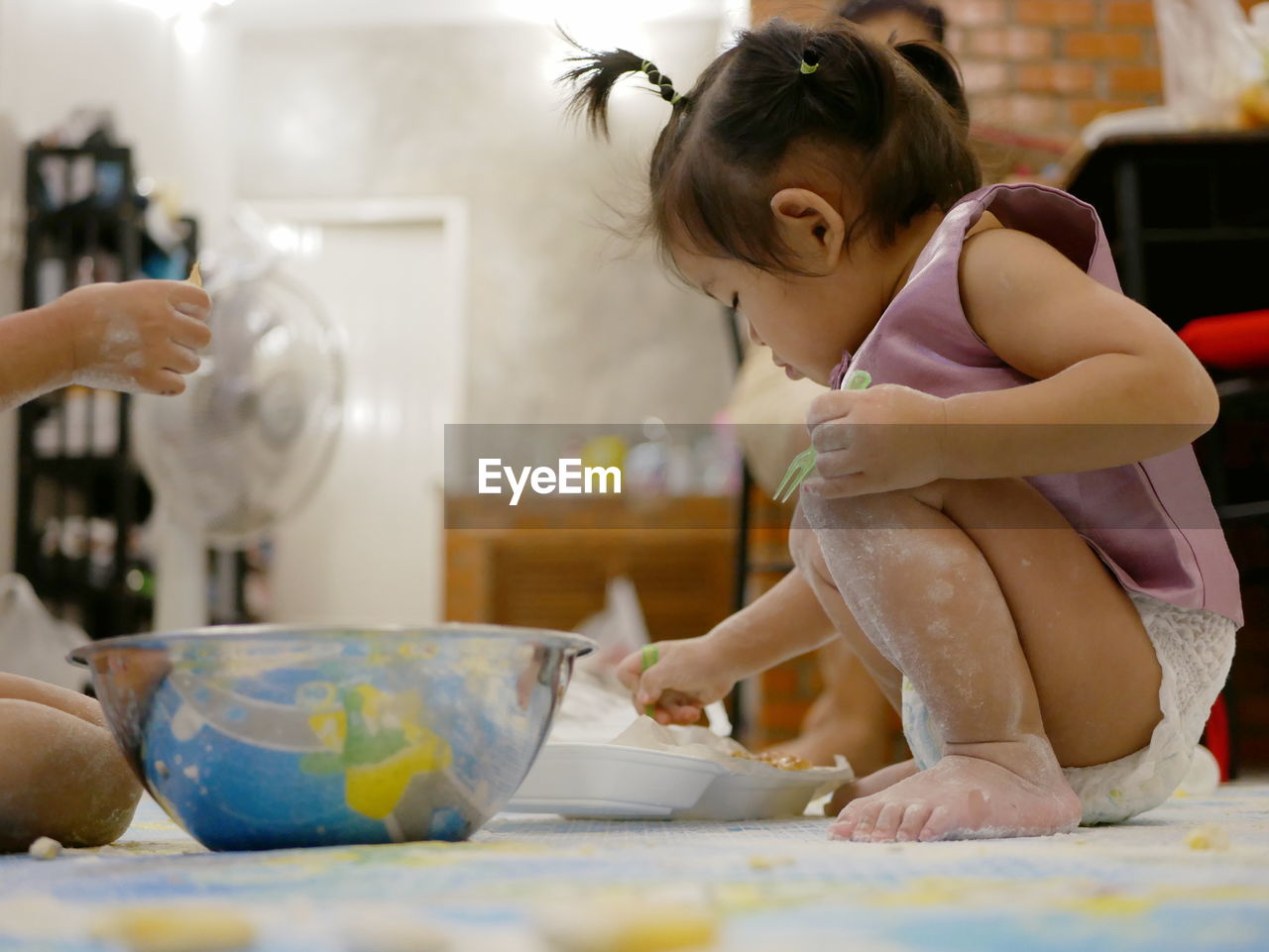 Baby preparing food while sitting on floor