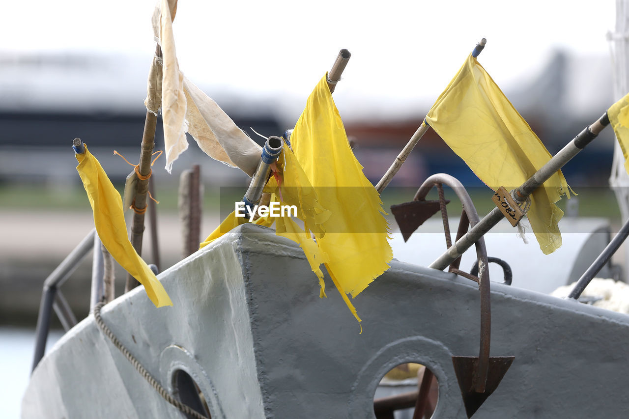 CLOSE-UP OF YELLOW FLAG HANGING ON BOAT