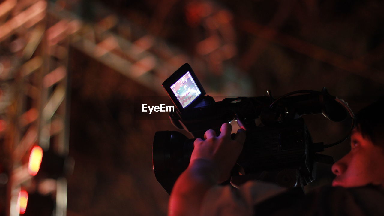 Low angle view of man filming with movie camera at night