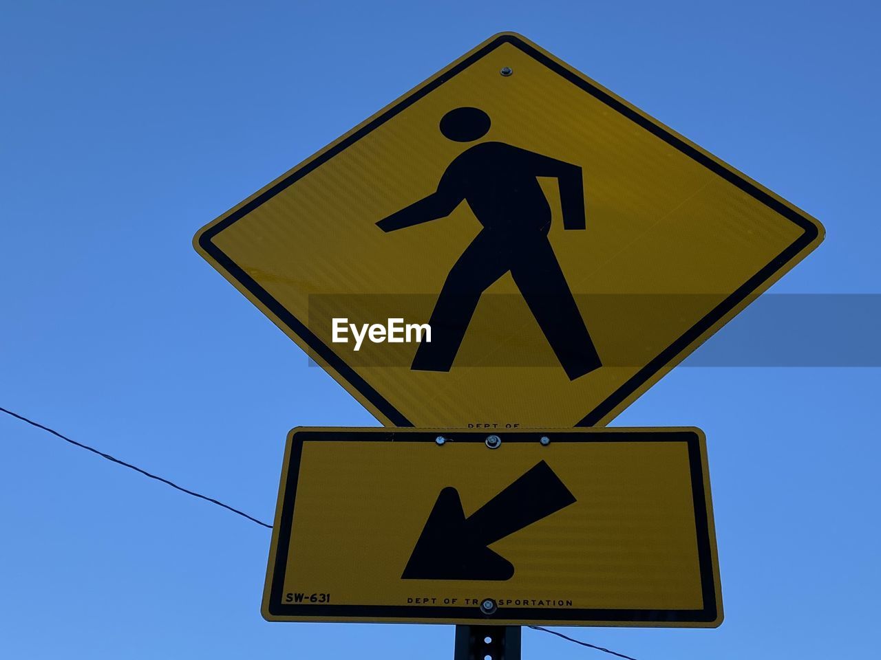 Low angle view of pedestrian crossing road sign against clear blue sky in mount vernon new york 