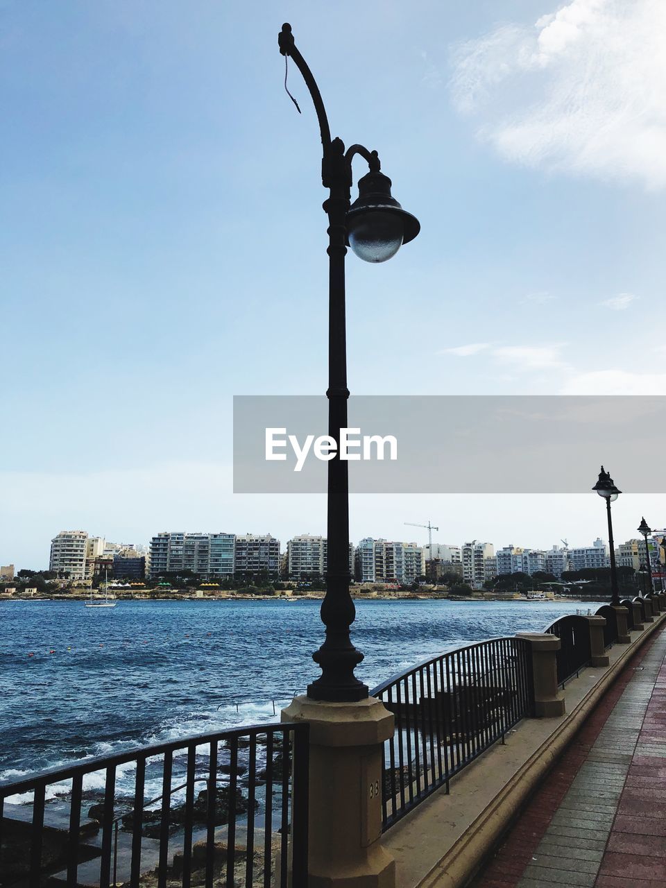 Street light by sea against sky