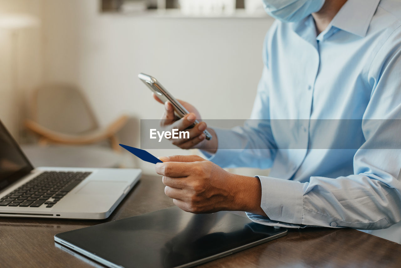 midsection of doctor using laptop while sitting at home