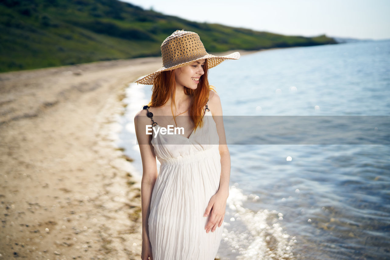 YOUNG WOMAN WEARING HAT STANDING IN WATER