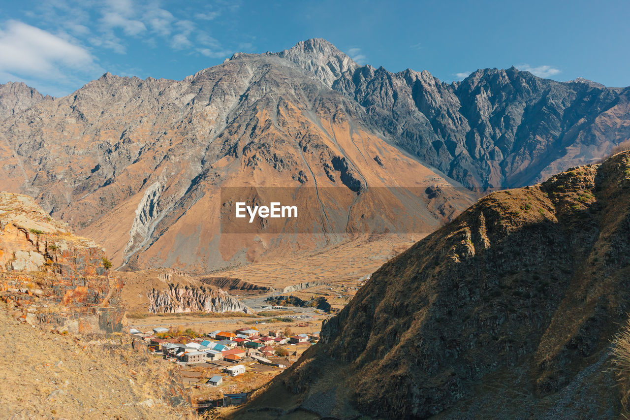 Stepantsminda, kazbegi, goergia. cityscape of big rural town with mountain range of mount kazbak.