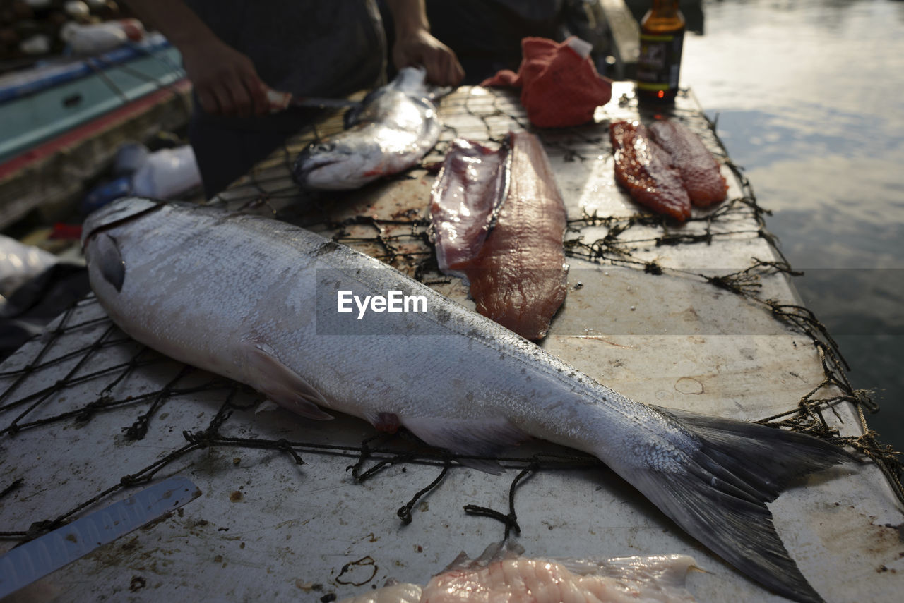 Midsection of fisherman cutting fish at table