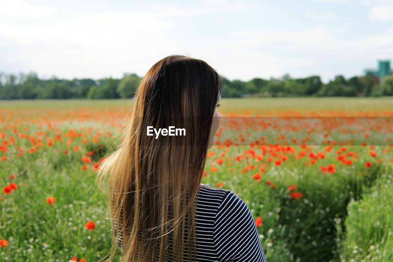 Rear view of woman standing on field against sky