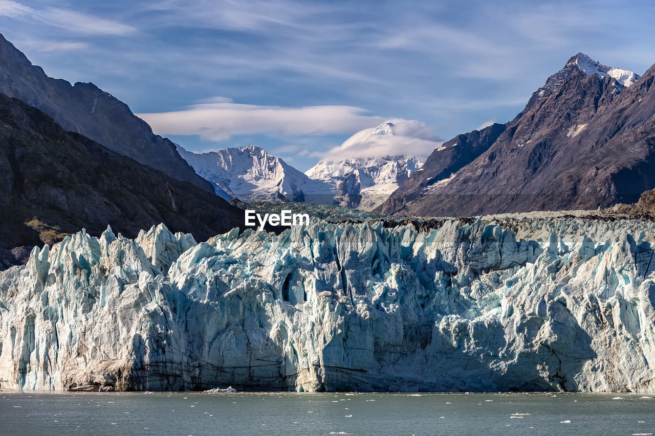 SNOW COVERED LANDSCAPE BY SEA AGAINST MOUNTAIN